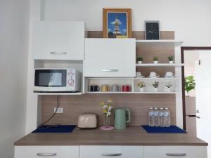 a kitchen with a counter with a microwave and water bottles at HAPPY SPACE Villa 2นอน 2น้ำ in Nakhon Phanom