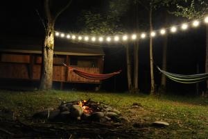 a fire in a yard with a hammock and lights at Jvarisa Glamping in Ambrolauri