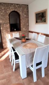 a white dining room table with white chairs and a stone wall at Holiday home Jaroje- 80m from beach in Pa&scaron;man
