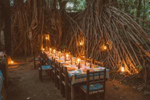 une longue table avec des bougies devant un arbre dans l'établissement Chole Mjini Treehouses Lodge, à Utende