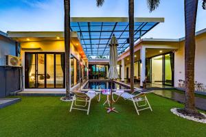 eine Außenansicht eines Hauses mit einem Pool und zwei Stühlen in der Unterkunft 4 Bedroom Modern Pool Villa BL10 in Hua Hin