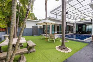 einen Hinterhof mit einem Pool mit einem Tisch und einem Sonnenschirm in der Unterkunft 4 Bedroom Modern Pool Villa BL10 in Hua Hin