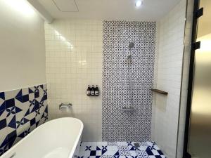 a bathroom with a tub and a shower with blue and white tiles at Green Inn Kaohsiung in Kaohsiung
