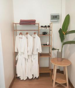 einen Kleiderständer mit weißen Hemden und einer Pflanze in einem Zimmer in der Unterkunft Himaphan Boutique Resort - SHA EXTRA PLUS in Nai Yang Beach