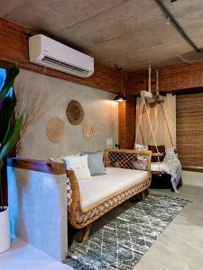 a wicker couch in a room with a air conditioner at Blue Tulip in Pusok