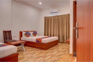 a bedroom with two beds and a table and a window at FabHotel Sri Udupi Park in Bengaluru