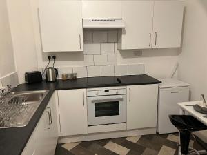 a kitchen with white cabinets and a stove top oven at Superb Lime Guest House in Shildon