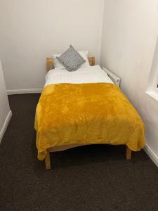 a bedroom with a bed with a yellow blanket at Superb Lime Guest House in Shildon