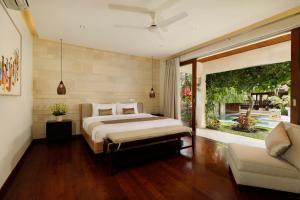 a bedroom with a bed and a couch at Villa Tenang by Nakula in Canggu