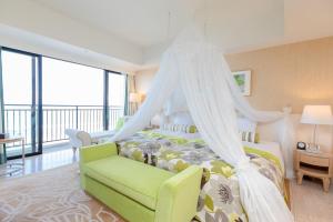 糸滿的住宿－南方海灘酒店，一间卧室配有天蓬床和绿椅