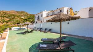 un patio con sedie, ombrelloni e piscina di Juan Manuel - Los Mangos El Borge by Ruralidays a Borge