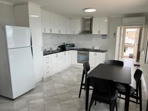 a kitchen with a table and a white refrigerator at Beachside & Jetty View Apartment 7 - Sea Eagle Nest Apartment in Streaky Bay
