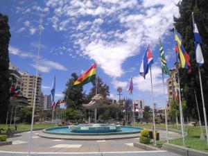 un montón de banderas en un parque con un edificio en Hostal Costa De Marfil Suites & Apartamentos, en Cochabamba