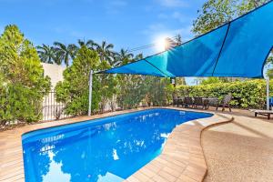 una piscina blu con un ombrellone blu sopra di Midlander Motor Inn a Emerald