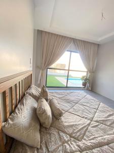 un grande letto in una camera da letto con una grande finestra di شاليه ريفان a Umm Lajj