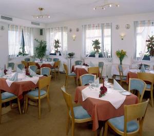 un comedor con mesas, sillas y ventanas en Hotel Ockenheim en Ockenheim