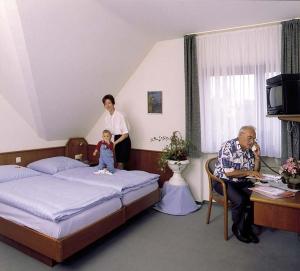 a woman and a man and a baby sitting on a bed at Hotel Ockenheim in Ockenheim