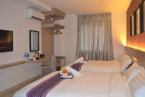 a hotel room with two beds and a desk at Ashley Boutique Hotel in Kota Damansara