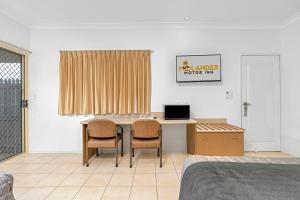 Midlander Motor Inn في إميرلاد: غرفة نوم مع مكتب مع كرسيين وسرير