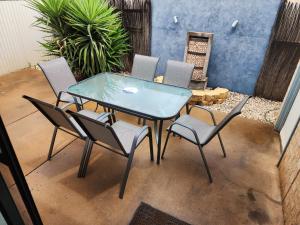 a glass table and chairs on a patio at Comfortable Villa across the road from the Historic Recreation Hotel in Kalgoorlie