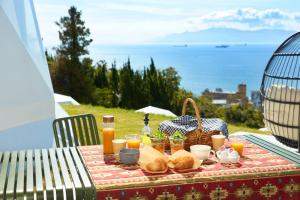 a picnic table with bread and juice and a view of the ocean at Dot Glamping 赤穂 in Ako