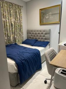 a bedroom with two beds with blue sheets and a desk at The Mews in Erith