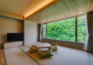 - un salon avec une table, des chaises et une grande fenêtre dans l'établissement Grand Blissen Hotel Jozankei, à Jozankei