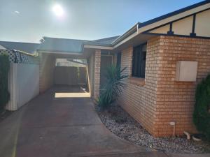 a brick house with a driveway in front of it at Comfortable Villa across the road from the Historic Recreation Hotel in Kalgoorlie