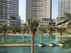 Gold Coast Apartemen PIK by Dluxx في جاكرتا: مسبح بالنخيل في مدينة ذات مباني طويلة