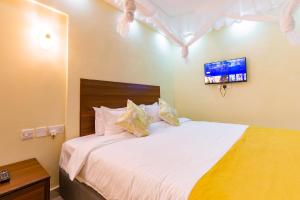 una camera con letto bianco e TV a parete di Marrkson Suites a Nairobi