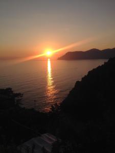 un coucher de soleil sur l'eau avec le soleil dans le ciel dans l'établissement L' Agave Cinque Terre, à Corniglia