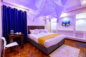 a bedroom with a large bed with blue curtains at Marrkson Suites in Nairobi +67 photos