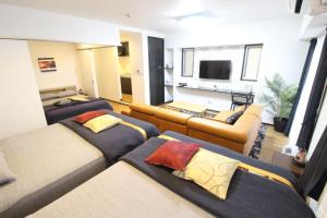 a room with three beds and a couch and a television at Condominium Felicita Naha in Naha