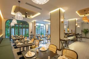 ein Restaurant mit Tischen, Stühlen und Fenstern in der Unterkunft Cozy Danang Boutique Hotel in Đà Nẵng