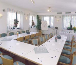 a room with white tables and chairs and a room with tables and chairs at Hotel Ockenheim in Ockenheim