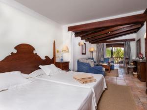 a bedroom with a large bed and a living room at Hotel Cala Sant Vicenç - Adults Only in Cala de Sant Vicenc
