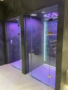 two glass shower stalls in a room with purple lighting at Woodside Apartment 431, Kopaonik - One separate bedroom 35m2- FREE Parking & SPA in Kopaonik