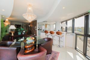 ein Wohnzimmer mit einem Glastisch und Ledersesseln in der Unterkunft Ocean View 505 Self Catering Accommodation Strand Western Cape South Africa in Strand