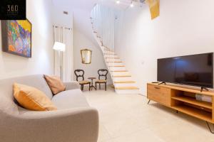 a living room with a couch and a tv and a staircase at LIVE like a Local - 3 Cities Home & 2 KING BED by 360 Estates in Cospicua