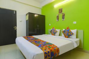 a bedroom with a large bed with green walls at FabHotel Broholic in Hyderabad