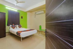 a bedroom with a bed and a green wall at FabHotel Broholic in Hyderabad