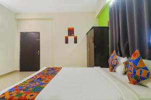 a bedroom with a large white bed with colorful pillows at FabHotel Broholic in Hyderabad