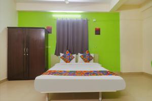 a bedroom with a bed and a green wall at FabHotel Broholic in Hyderabad