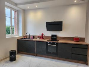 a kitchen with a counter with a tv on the wall at Maison face à l'abbaye d'Hautvillers - 2 bedrooms 2 Bathrooms, parking in Hautvillers