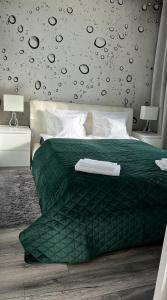 a bedroom with a bed with a green comforter at Apartament Winnica in Toruń
