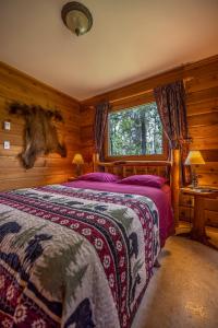 ein Schlafzimmer mit einem Bett in einem Blockhaus in der Unterkunft Mica Mountain Lodge & Log Cabins in Tete Jaune Cache