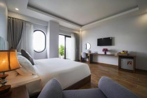 a hotel room with a large bed and a tv at The May Phu Quoc Hotel in Phú Quốc