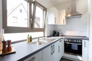 cocina con armarios blancos, fregadero y ventana en Appartement Champagne en Neuenstadt am Kocher