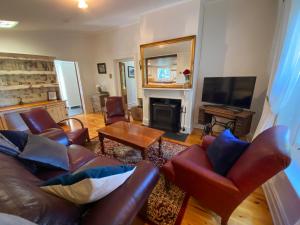 sala de estar con muebles de cuero y chimenea en Stirling Cottage, en Stirling