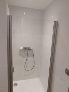 La salle de bains est pourvue d'une douche blanche avec un tuyau. dans l'établissement Agréable maison au centre d'Arreau pour 8 pers, à Arreau
